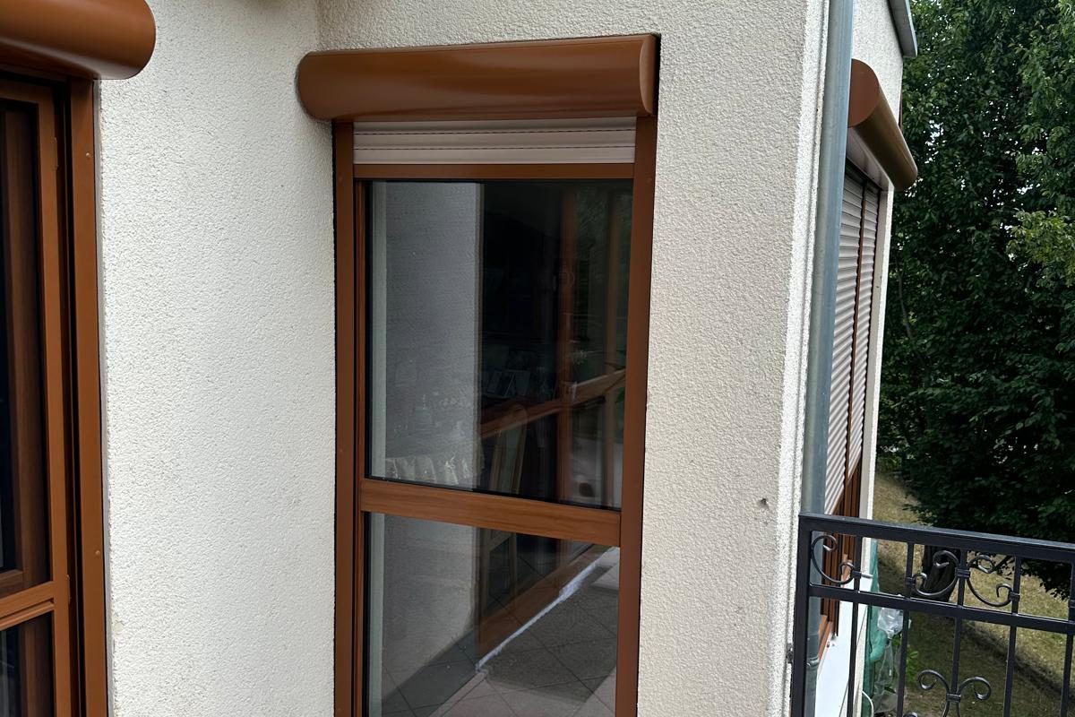Fenstertür in Holzdekor mit Rollladenkasten an einer hellen Fassade