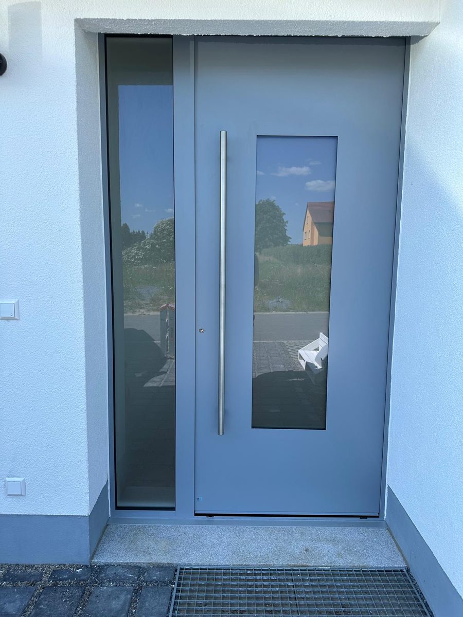 Graue Haustür mit Glaseinsatz, Stangengriff und Glas-Seitenteil